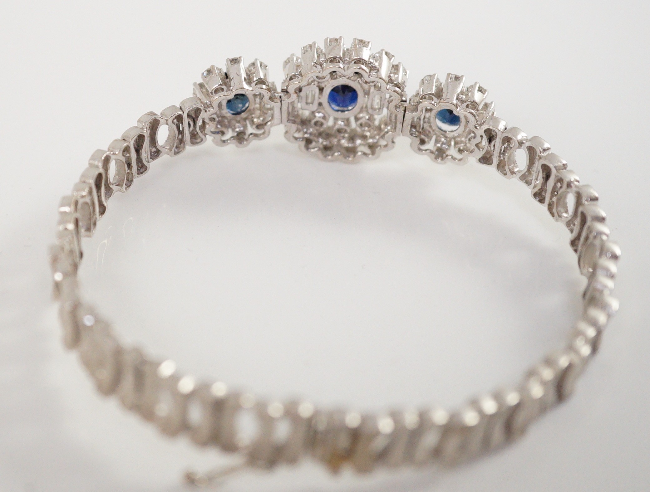 A mid to late 20th century textured 18k white gold, sapphire, round and baguette cut diamond set triple oval cluster bracelet